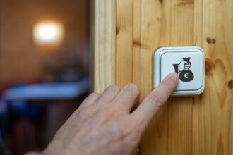 Ręka mężczyzny włączająca żarówkę z symbolem wysokich kosztów energii elektrycznej z powodu inflacji